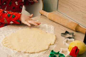 Cute caucasian boy in red pijamas making cookies in the kitchen