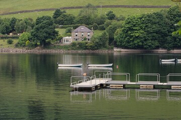 a boat dock with boats a reservoir a green waterfront with a beautiful old country house and trees around it
