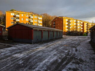 Residential area with garages and apartment buildings under cloudy sky during late afternoon light