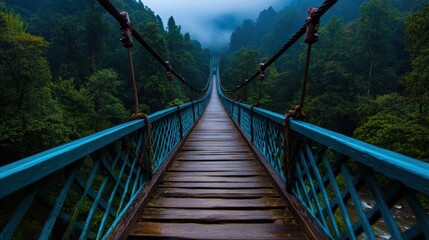 This atmospheric image showcases a suspension bridge enveloped in mist, leading into a lush forest, capturing the eerie beauty of nature and a sense of adventure.