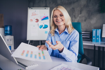 Confident senior businesswoman analyzing charts in modern office with natural daylight