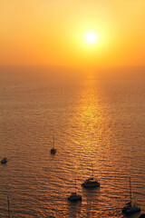 Yachts in the Aegean Sea against the backdrop of sunset near the Santorini island.