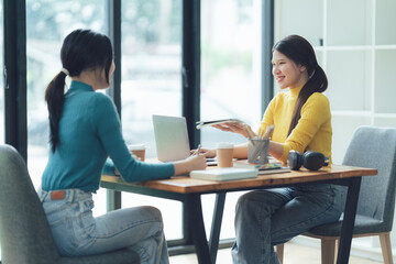 Fototapeta premium Two Young Women Collaborate and Discuss Ideas: A captivating image of two young women engaged in a lively conversation.