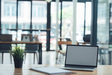 Fototapeta premium Modern Workspace Minimalism: Laptop with blank screen on wooden desk in a blurred modern office background. Perfect for showcasing your projects or designs. 