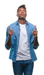 Fototapeta premium Young african american man over isolated background amazed and surprised looking up and pointing with fingers and raised arms.