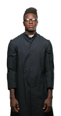 Young african american priest man over isolated background with serious expression on face. Simple...