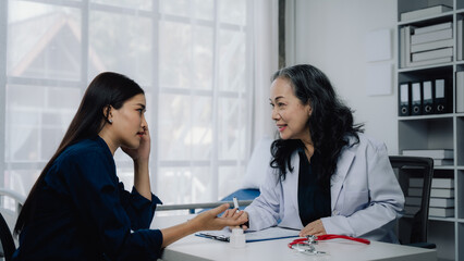 Obraz premium Doctor and Patient Conversation: A doctor listens intently to her patient, creating a warm and empathetic atmosphere in a professional office setting. Their smiles exude a sense of trust and care. 