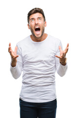 Fototapeta premium Young handsome man over isolated background crazy and mad shouting and yelling with aggressive expression and arms raised. Frustration concept.