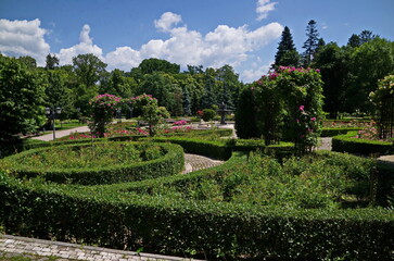 A beautiful relaxation area with a bench, a fountain and flowering bushes in the rose garden, Sofia, Bulgaria 
