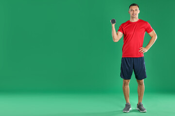 Man exercising with dumbbell on green background, space for text © New Africa