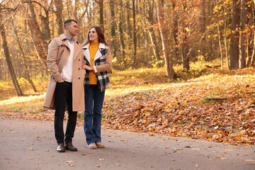 Fototapeta premium Happy couple spending time together in autumn park, space for text