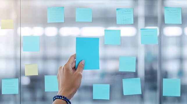 Hand Placing Blue Note on Glass Board, Hands sticking notes board ideas concept.