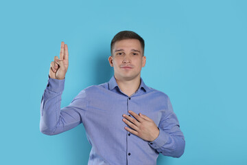 Man showing oath gesture on light blue background. Making promise