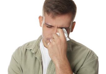 Crying man wiping tears with tissue on white background