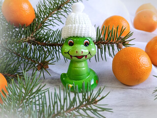 Toy snake among tangerines and pine branches, close-up