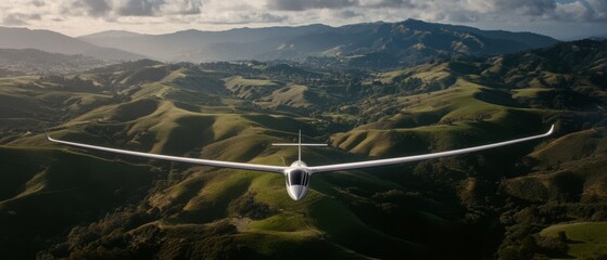 A sleek glider soars majestically over lush, rolling hills under a cloud-dappled sky, epitomizing freedom and the art of flight.