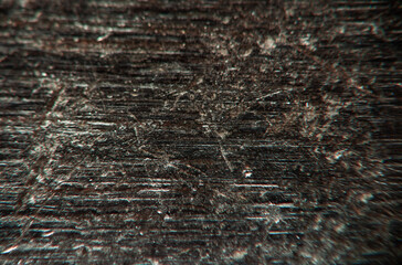 Textured surface of worn wood showing scratches and lines in dim lighting conditions