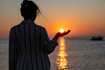 Fototapeta premium Woman Holding Sunset over Water