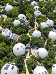 Aerial View of Eco-Village with Futuristic Geodesic Domes and Solar Panels Amidst Lush Greenery  