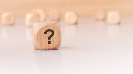 A wooden block with a question mark on a minimal background creates intrigue and prompts thought