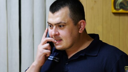 Male firefighter chief have serious telephone conversation with his subordinate by smartphone at...
