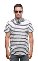 Handsome young man wearing headphones skeptic and nervous, frowning upset because of problem....