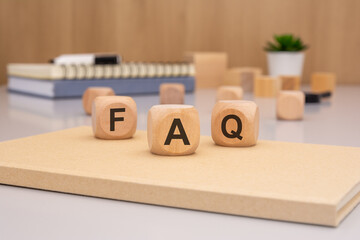 A set of Wooden FAQ Letters placed on a Notepad in a contemporary Office Setting