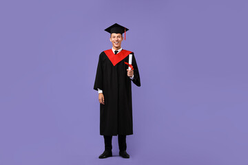 Happy student with diploma after graduation on violet background