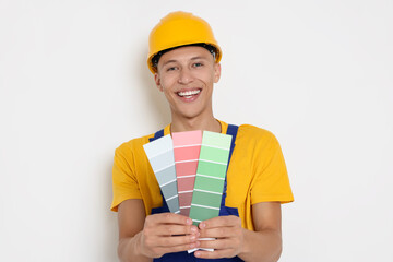 Portrait of young decorator with color palettes on white background