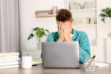 Student with headphones studying at table indoors