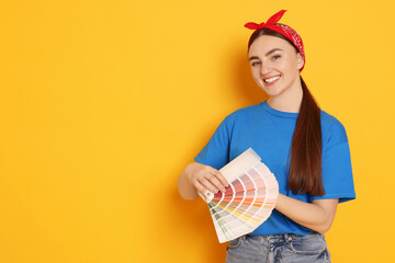 Portrait of young decorator with color palettes on orange background, space for text