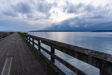 Obraz premium Scenic Wooden Pier Overlooking Ocean with Calm Waters and Cloudy Skies