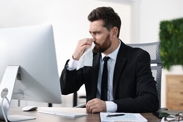 Naklejka premium Sick man with runny nose at table in office