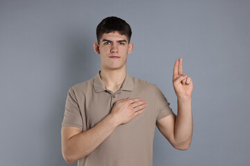 Fototapeta premium Man showing oath gesture on grey background