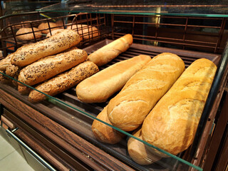 Fresh baguettes on a bakery display. Artisan bread shop with crispy golden loaves. Wheat baguettes...