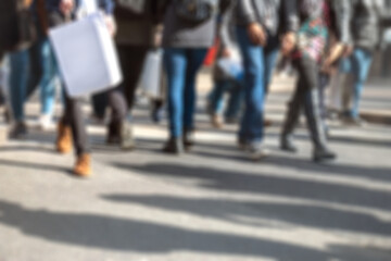 Pedestrians &ndash; feet of people walking on busy city street sidewalk. Abstract urban scene depicting crowd of multicultural shoppers on metropolitan road carrying shopping bags. Intentionally blurred.