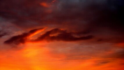 Obraz premium Abstract dark red and yellow sky background with burning sky effect, and rays of sunlight during sunset. Topics: hot colors, cloudy background, weather, meteorology, climate, air space, atmosphere