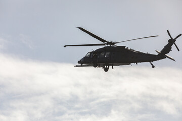 Sikorsky UH-60 Black Hawk helicopter flies over  Cape Disappointment, silhouetted against a...