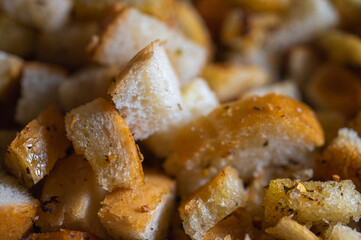 Golden-brown croutons, seasoned with herbs, create a delicious texture and crunch. Perfect close-up shot of bread cubes for cooking, recipes, or food backgrounds