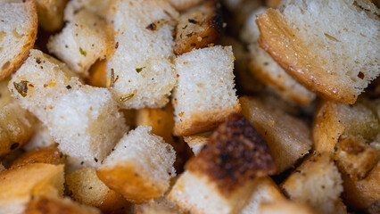 Golden-brown croutons, seasoned with herbs, create a delicious texture and crunch. Perfect close-up shot of bread cubes for cooking, recipes, or food backgrounds
