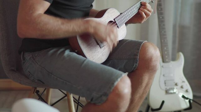 4K close up Ukulele or uke string instrument video popular on Hawaii islands. Man playing nylon strings during music lessons. Musical education and art people concept footage.