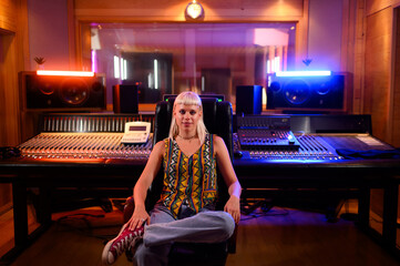 Portrait of female sound technician at music studio with channel mixer