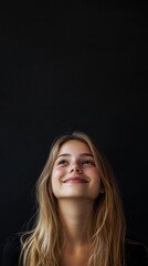 Fototapeta premium beautiful young girl smiling looking up on black background with copy space vertically 9:16