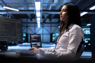 Developer using computer to troubleshoot hardware and software issues in server room. IT...