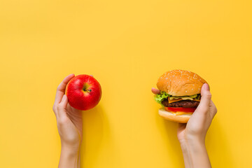 Healthy diet vs fast food. Choosing an apple or burger. Isolated on yellow background. High quality photo