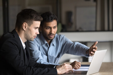Two Indian and Caucasian businessmen, partners discussing online project progress, reviewing...