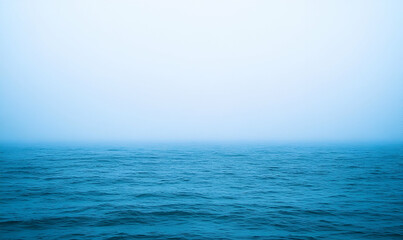 Obraz premium A serene view of a foggy sea blending into the horizon.