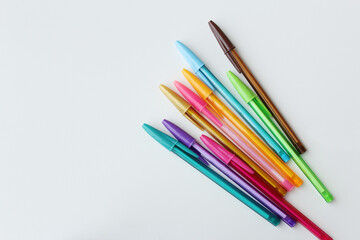 Fototapeta premium Bunch of colorful pens arranged in diagonal on white background. Color stationery, school supplies, art lesson, creativity concept. 