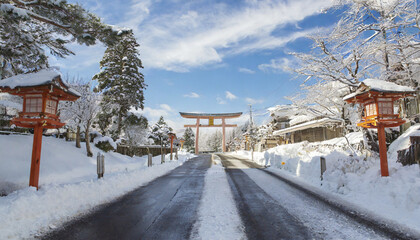 Fototapeta premium 冬・雪が降り積もった田舎道 青空と冬の空に道路の奥の鳥居 正月・年末年始・新年・初詣