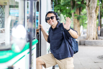 Fototapeta premium Smiling Traveler Male Taking Tourist Bus While Greeting With Waving Hand